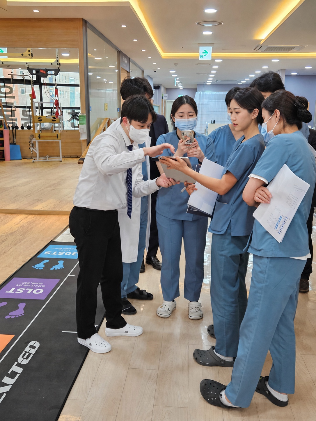 의료진과 물리치료사가 NEUROGAIT 앱과 평가 매트를 함께 확인하는 장면